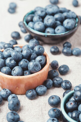 Three ceramic bowls with blueberries and berries scattered around.