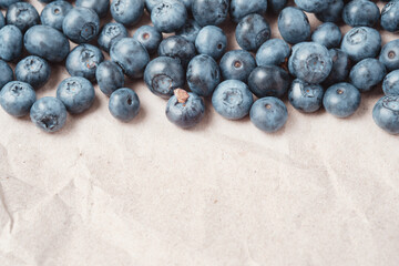 Fresh blueberries scattered on beige craft paper.