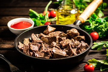 A frying pan with cooked liver on the table. 