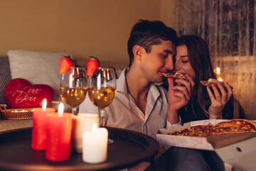 Valentines Day couple in love eating pizza drinking champagne enjoying romantic dinner celebrating...