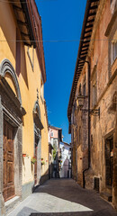 The small medieval village of Corchiano, in the province of Viterbo, in Lazio. The narrow streets of the small town with the old brick houses. The blue sky on a sunny day in summer.