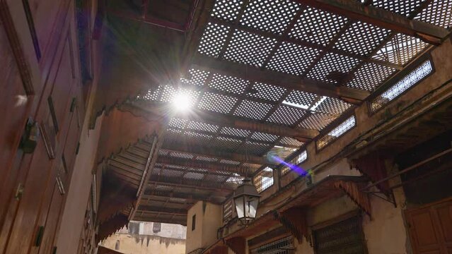 Interior of local market in Fez, Morocco. Massive doors of counters are closed on padlocks. From above, market is covered with iron gratings with small cells that scatter rays of scorching sun.