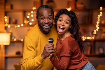 Funny black couple enjoying singing karaoke at home