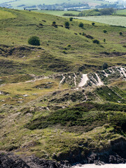 Obraz premium Picturesque dunes with shrubs and hills in the Ireland on a sunny day. North European seaside landscape. Nature of Ireland.