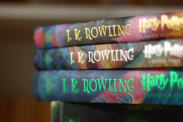 Fototapeta premium Split, Croatia - January 15, 2023: Stack of fantasy books by famous author J. K. Rowling. Bookshelf in the background. Selective focus.