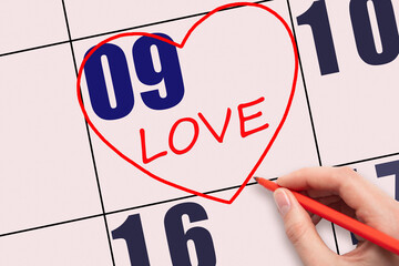 9th day of the month. Hand writing text LOVE and drawing a red heart on a pink calendar date.