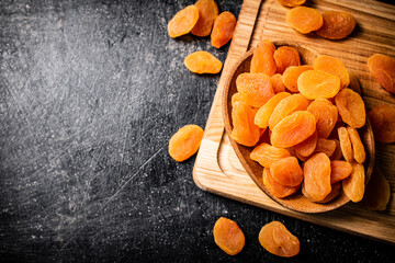 Dried apricots in a plate on a cutting board. 