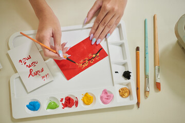 Hands of woman painting red lucky money envelopes for spring festival