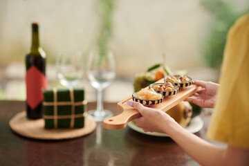 Woman carrying cutting board with fermented onion and daikon to Tet dinner table