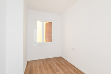 Part of an empty room with white walls, brown parquet. A plastic window in the wall with frosted translucent glass