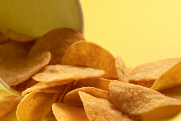 Potato chips scattered on the table close-up on a yellow background. Food with elevated cholesterol levels