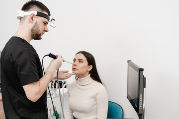 Nose endoscopy. Rhinoscopy procedure with rhinoscope. ENT doctor otolaryngologist with headlight...