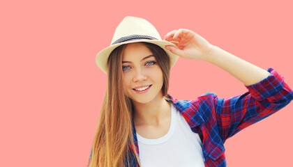 Portrait of beautiful smiling woman wearing summer straw hat on pink background