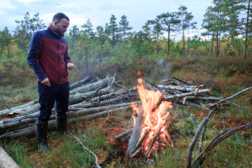 Obraz premium The traveler stands near the fire in the forest, fire, halt.