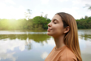 Reconnect with nature. Side view of young woman with closed eyes enjoying breathing in tropical park of Brazil.