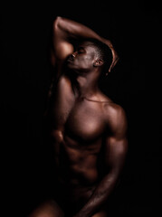 Fototapeta premium Sensual, nude and black man on dark background with muscular body, natural or dim light. Confident, African American male or strong person shirtless, athletic or bodybuilder with wellness or creative