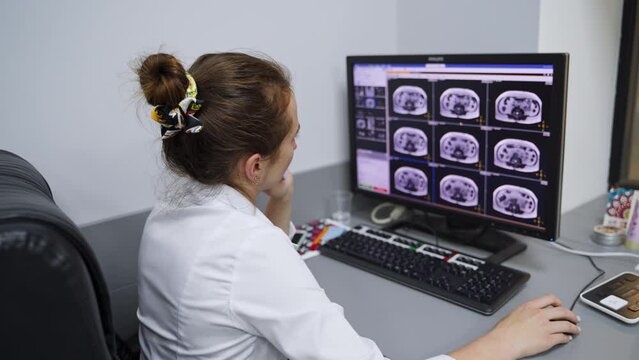 Doctor sitting at the computer table looking at similar head scans. Medic analyzing the results of magnetic resonance imaging.