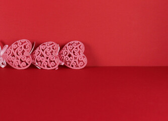 Decorative pink hearts lie on a red monochromatic background, Valentine's Day