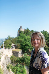 Young beautiful woman smiles against the backdrop of the Guaita Fortress, San Marino, Italy