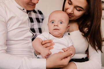 Little boy pop-eyed surprised cute child baby playing with parents, sitting on knees. Playful shocked toddler with bulging eyes having fun, making faces grimaces. Happy childhood, family concept
