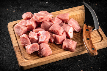 Pieces of raw pork on a wooden cutting board with a knife.  - 564032736