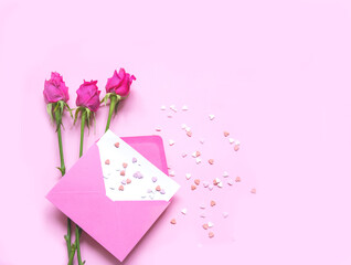 Pink envelope with decorative hearts and rose flowers on pink background. Festive background concept for Valentine's Day. Close-up
