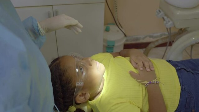 Video Of A Little Latina Girl Lying On A Seat Inside A Dental Office While Her Transgender Doctor Treats Her.