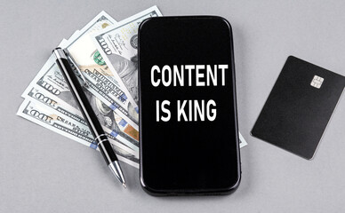 Credit card and text CONTENT IS KING on smartphone with dollars and pen. Business concept