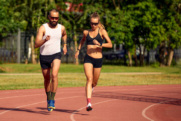 Woman and man jogging in the stadium - Powered by Adobe