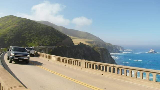 Close up shot of bright neon green color off road car, SUV vehicle, trucks driving by Pacific Coast Highway. West coast road trip. Scenic road landscape at Bixby Bridge, California, USA RED camera 4K