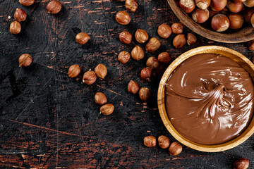 Hazelnut butter and inshell hazelnuts on the table in plates.