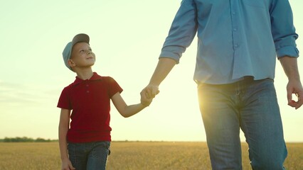 Little son and dad hold hands close-up in nature in sun. Happy family, teamwork. Adoption of child. Parent, kid boy outing together. Child father walk in autumn park at sunset, family trust concept.