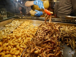 Woman behind counter at Mercado de San Miguel putting mixed fried seafood in bags. Madrid, Spain.