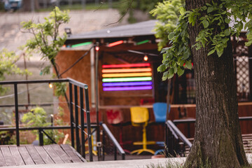 Fototapeta na wymiar Tree on the background of beach bar booth with rainbow neon