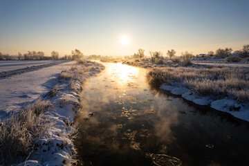 Winter sunrise over a misty river. winter morning by a steaming river. Sunny morning over a steaming river.