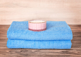 Fototapeta na wymiar Folded blue towels and a pink candle on a wooden table