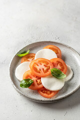 Caprese salad with tomatoes, basil, mozzarella. Traditional Italian food on white background, copy space