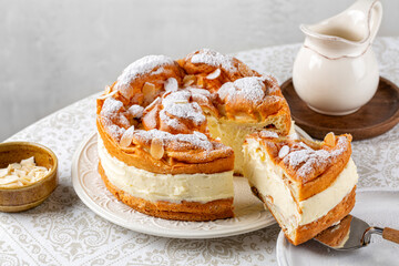 Cream puff cake Karpatka on a round table. Polish Carpathian mountain custard, sandwiche, cream cake. Consists of two layers of choux pastry with almonds and powdered sugar. - obrazy, fototapety, plakaty