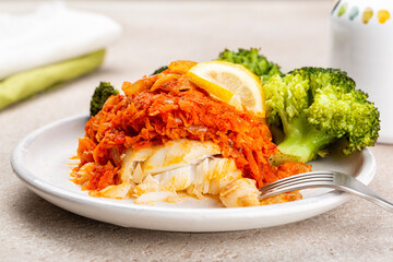 Greek and Polish style oven baked cod fish Psari Plaki with sauteed, shredded vegetables, carrot,...