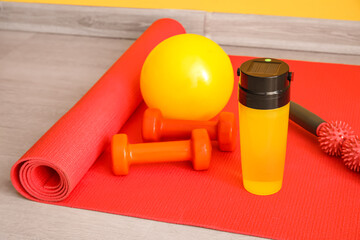 Sports water bottle with equipment on mat, closeup