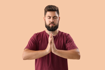 Handsome young man meditating on beige background