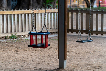Fototapeta na wymiar Children's playground in the park. Empty swing in the wooden playground.
