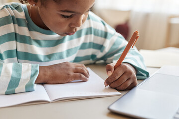 Black girl writing in notebook doing homework at desk