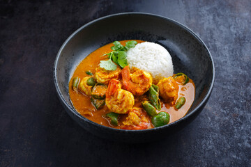 Traditional Thai kaeng phet red curry prawn with chili and basmati rice served as close-up in a Nordic design bowl