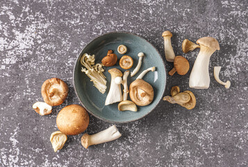 Bowl with different fresh mushrooms on grunge background