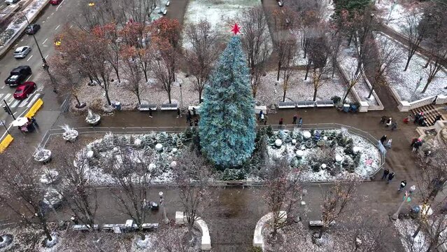 Drone aerial shot flying over Christmas tree in Millennium Park, Chicago on snowy winter day