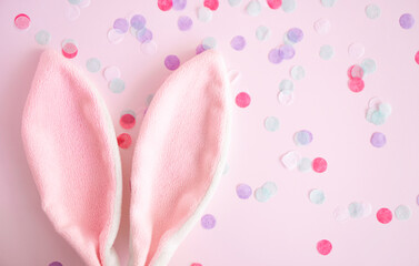 Easter greeting card  .Pink  bunny ears  on pink  pastel background  wint confetti with,  copy spase  . Easter minimal concept. Flat lay. advertising concept .