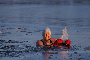 Winter swimming. Mature woman in frozen lake ice hole. Swimmers wellness and endorphin booster swim...