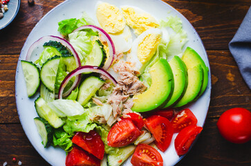 Tuna Salad, Healthy Food, Fresh Salad with Lettuce, Avocado, Cherries, Cucumber and Eggs on a Plate on Wooden Background