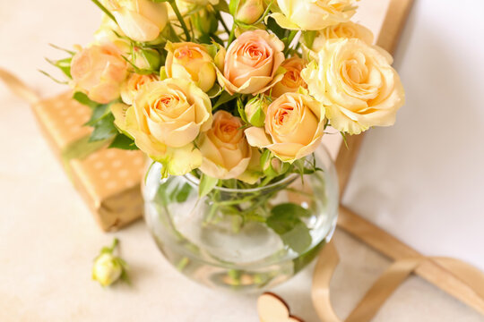 Glass vase with beautiful rose flowers on light background, closeup